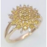 A 9K YELLOW GOLD, WHITE AND YELLOW DIAMOND SET CLUSTER RING. 3.3G. SIZE L 1/2. A MIXTURE OF ROUND