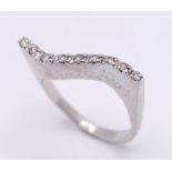 An 18K White Gold Diamond Wave Ring. Nine diamonds on the crest of a wave. Size M. 5.43g total