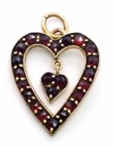 A 9 K yellow gold , heart shaped pendant loaded with garnets, height (with bail): 29 mm, weight: 2.5