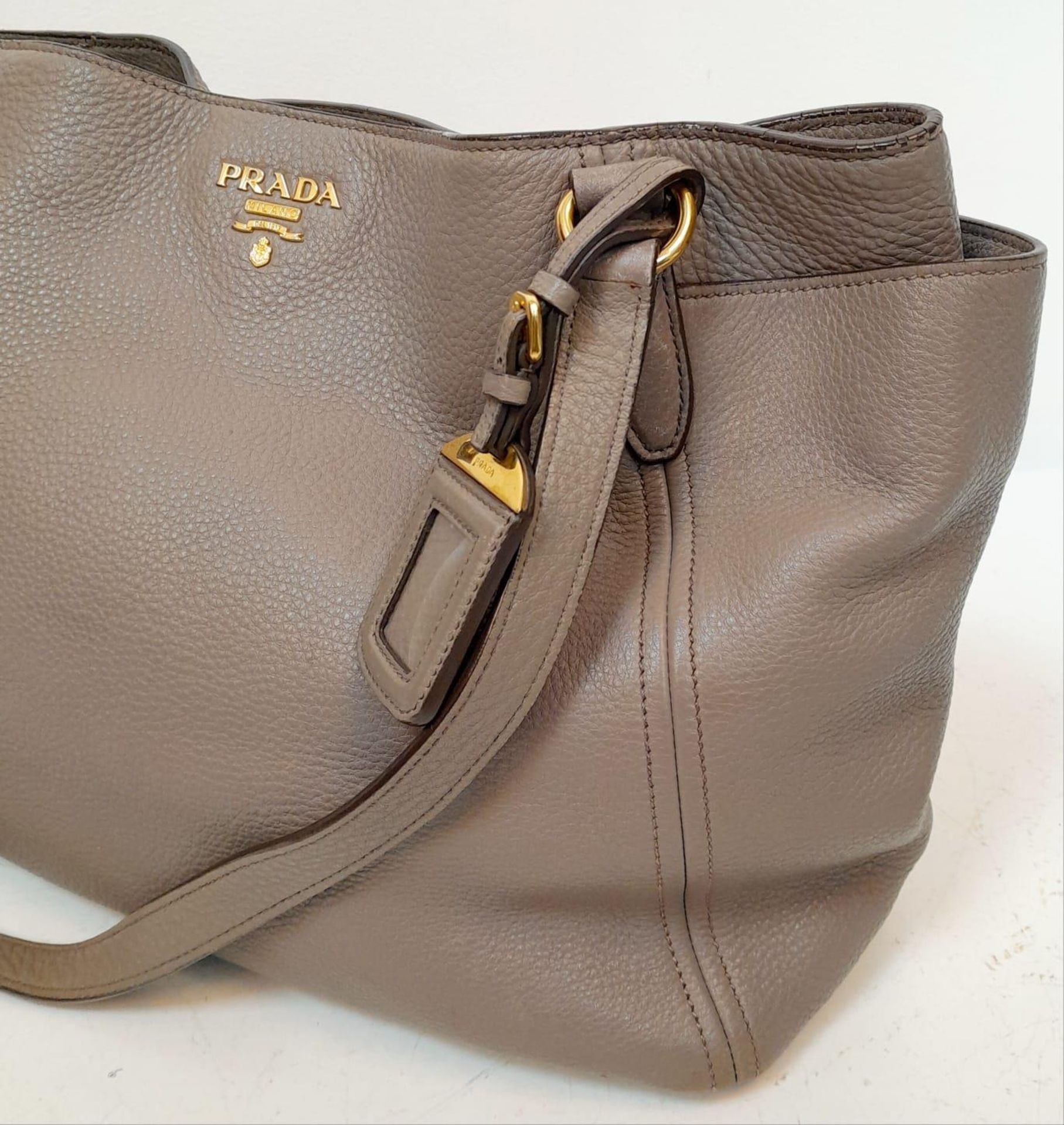 A Prada Grey Leather Shoulder Bag. Textured leather exterior with gold tone hardware. Textile and - Image 2 of 9