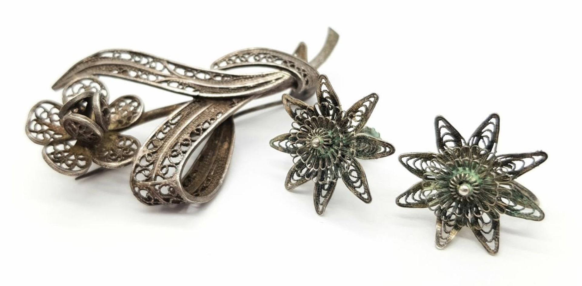 A matching set of sterling silver floral filigree brooch and a pair of screw earrings. Total