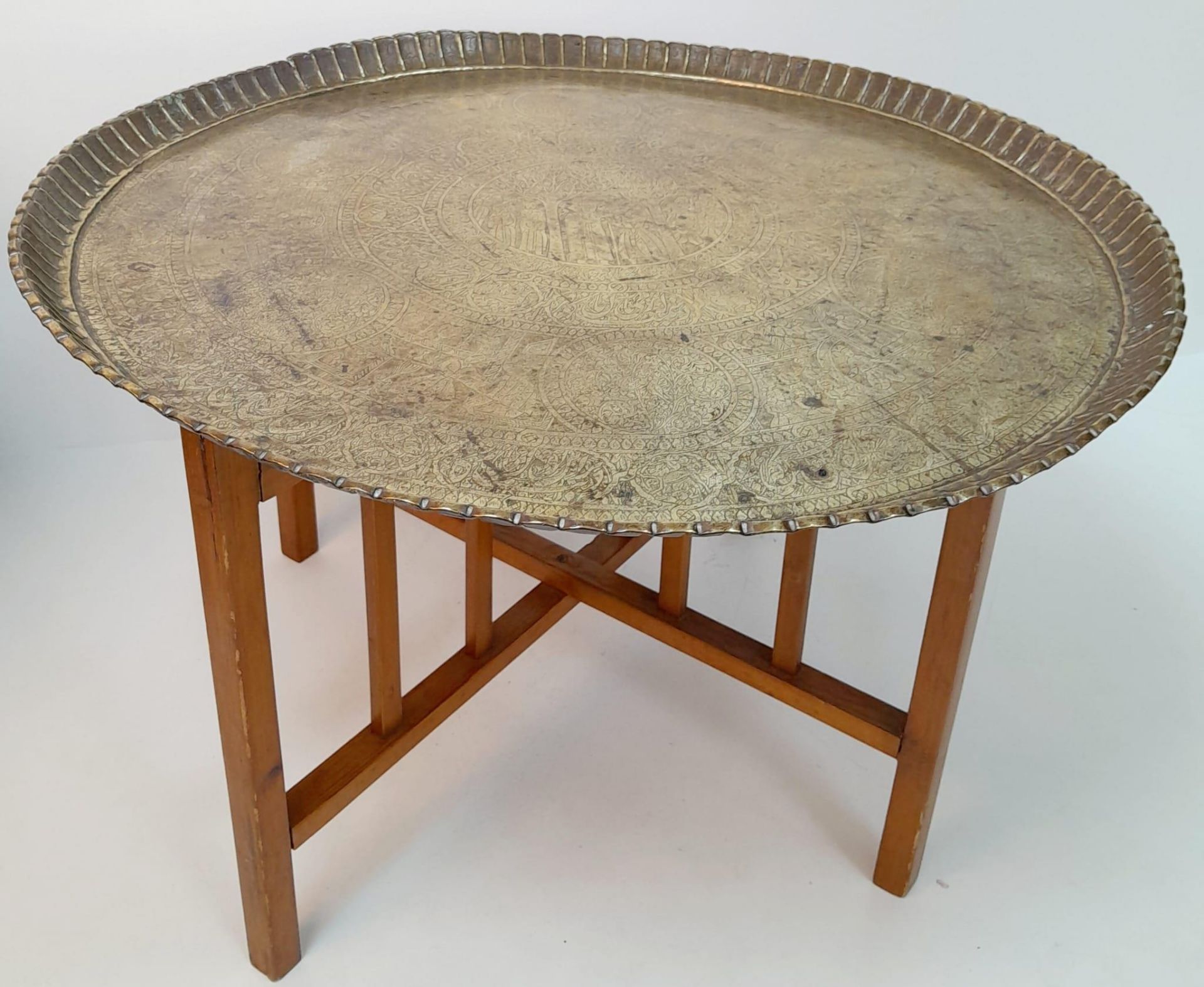 A MIDDLE EASTERN BRASS TOPPED TABLE WITH FOLDING WOODEN LEGS . 52cms TALL 76cms DIAMETER. Collection