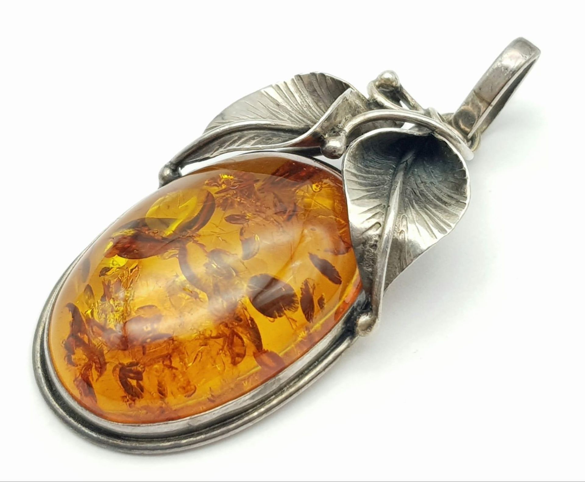 A Vintage 925 Silver and Amber Brooch. A rich amber cabochon amongst silver leaves. 6cm. 11.5g total