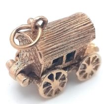 A 9 K yellow gold charm with a gipsy caravan, which when opened reveals a gipsy consulting her