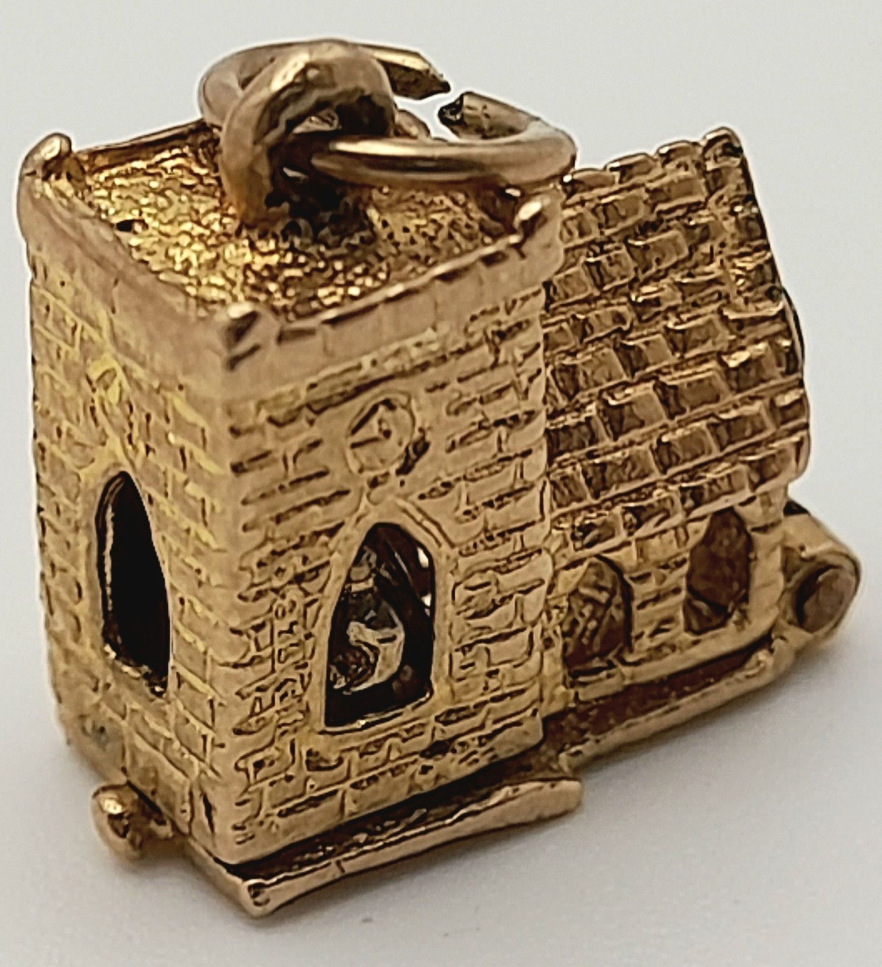 A 9 K yellow gold charm in the shape of a chapel, which opens to reveal a wedding ceremony,