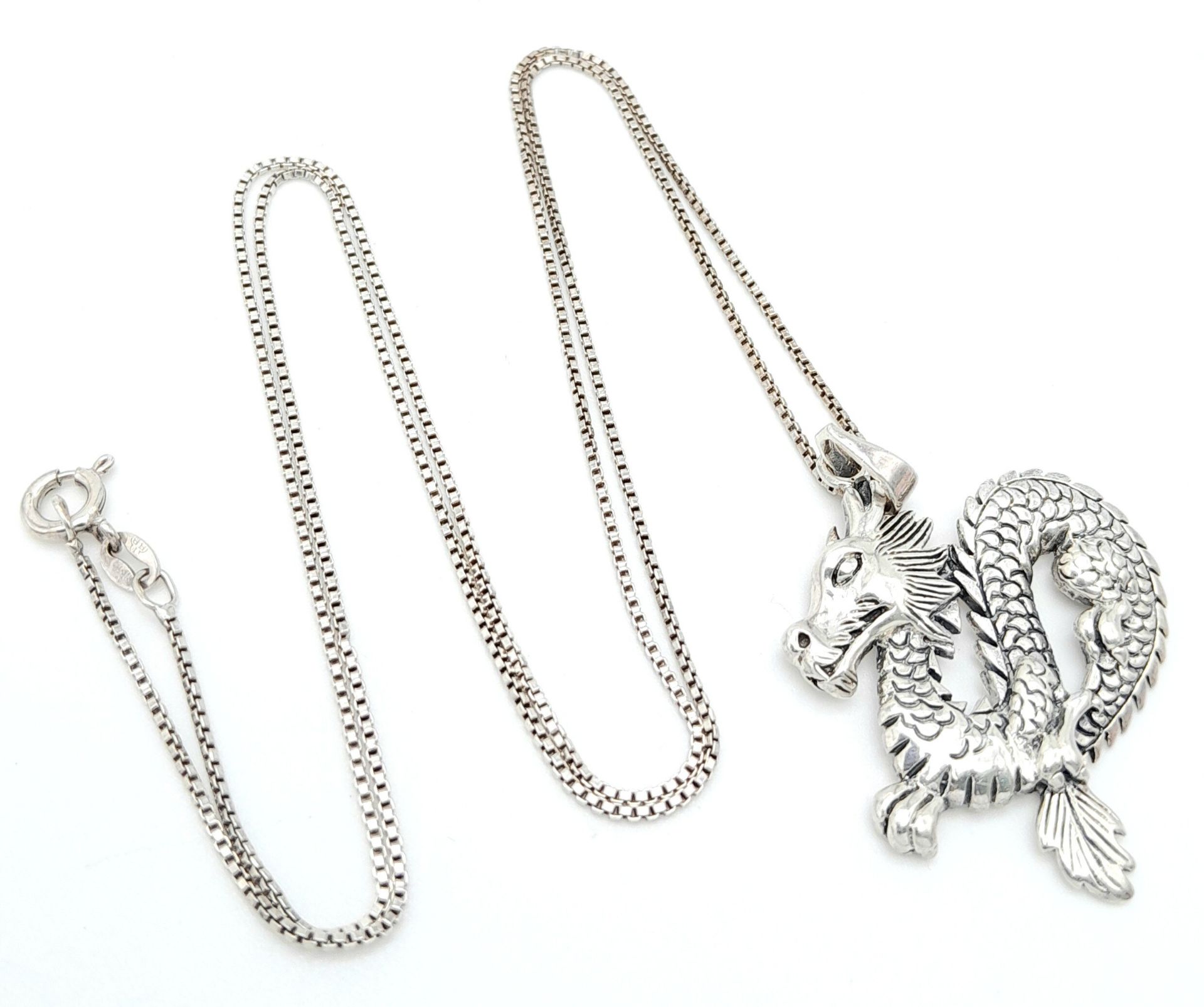 A Sterling Silver Dragon Pendant on 925 Silver Chain. 4.5cm pendant, 62cm chain. 9.7g total weight.