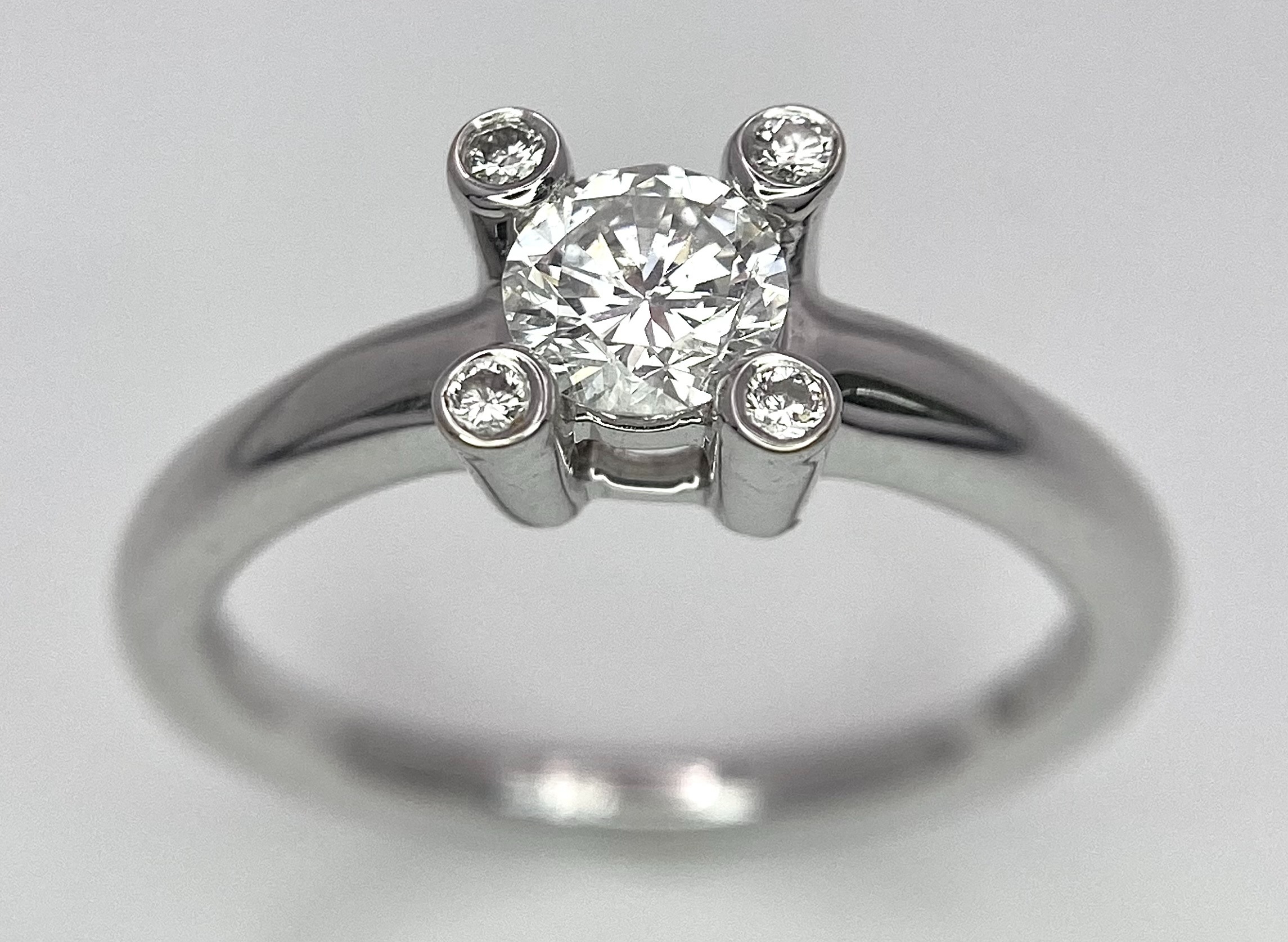 AN 18K WHITE GOLD DIAMOND SOLITAIRE RING WITH FOUR DIAMOND TURRETS - 0.50CT 4.6G. SIZE M 1/2.