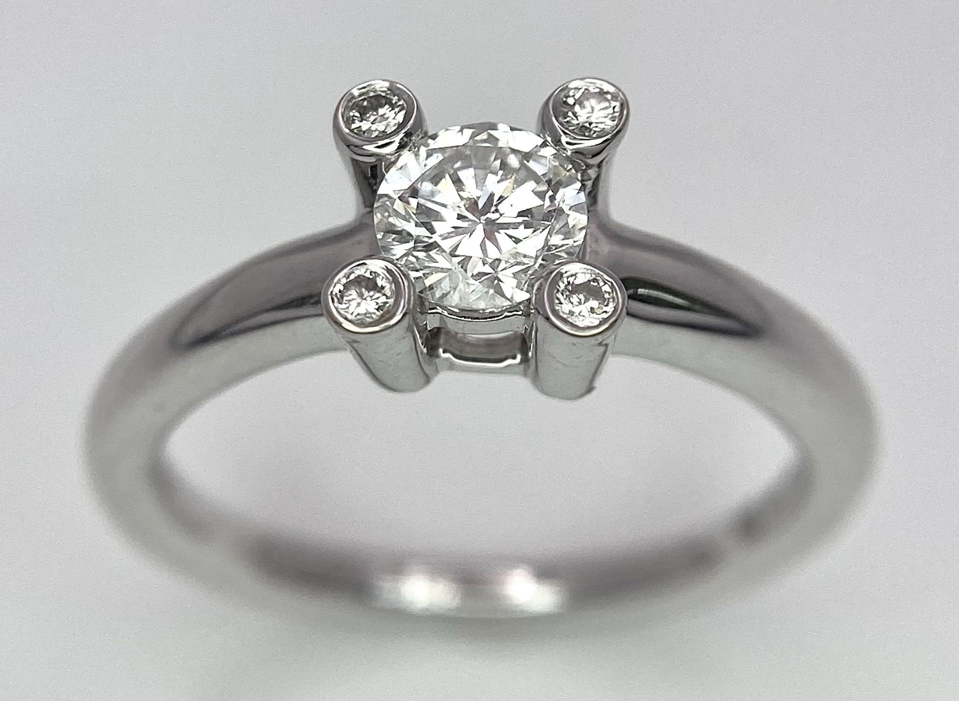 AN 18K WHITE GOLD DIAMOND SOLITAIRE RING WITH FOUR DIAMOND TURRETS - 0.50CT 4.6G. SIZE M 1/2.