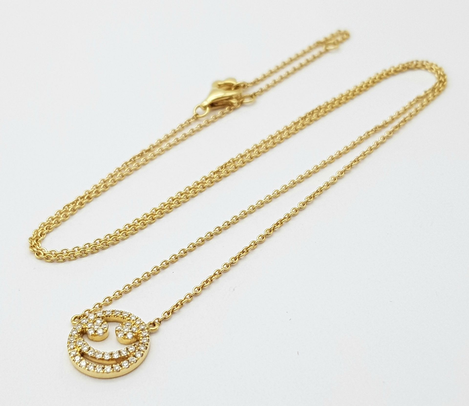 An 18K Gold Diamond Smiley Face Pendant on an 18K Yellow Gold Disappearing Necklace. 1cm diameter
