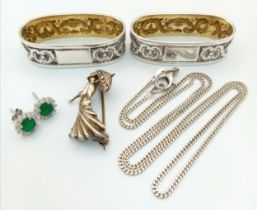 A Silver Mixed Lot: Lady with umbrella brooch, 48cm necklace, two thin table napkin holders and a