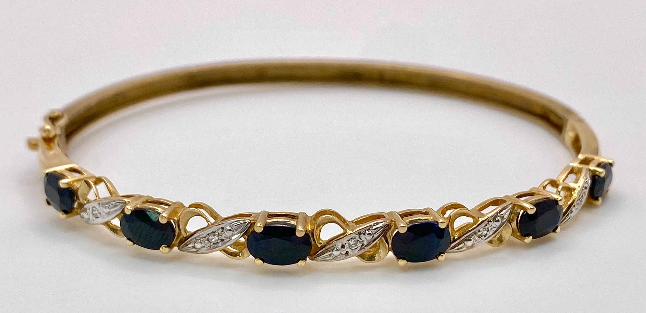 A Vintage 9K Yellow Gold Sapphire and Diamond Bangle. Six oval cut sapphires with diagonal - Image 2 of 6