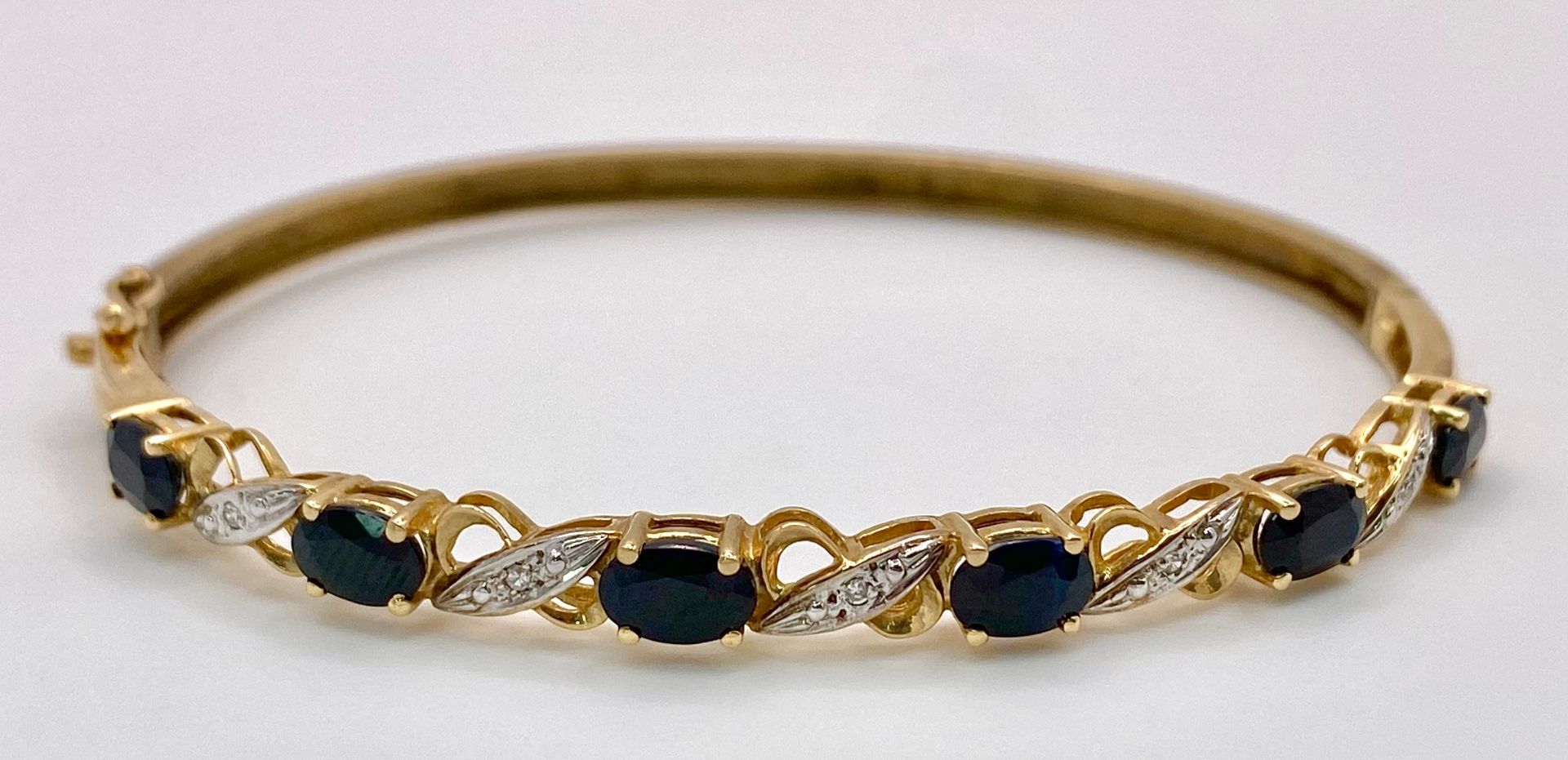 A Vintage 9K Yellow Gold Sapphire and Diamond Bangle. Six oval cut sapphires with diagonal - Image 2 of 6