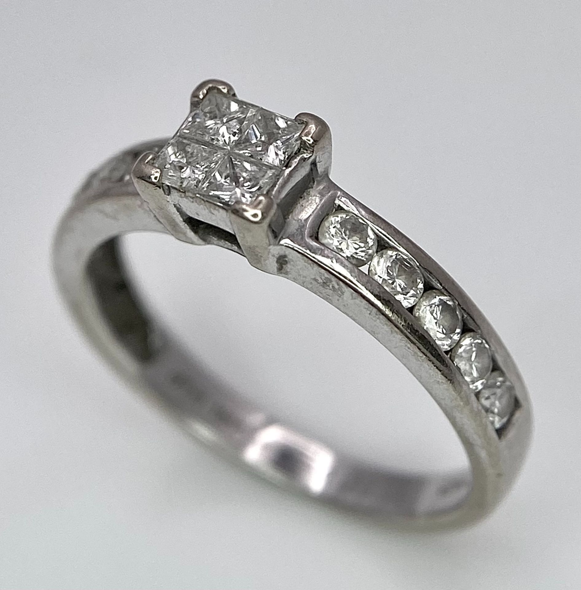 An 18K White Gold and Diamond Ring. Square and round cut diamonds. Size J. 2.6g total weight.