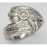 An 18K White Gold Diamond Fancy Crossover Ring. Two encrusted diamond crossover waves meet at the