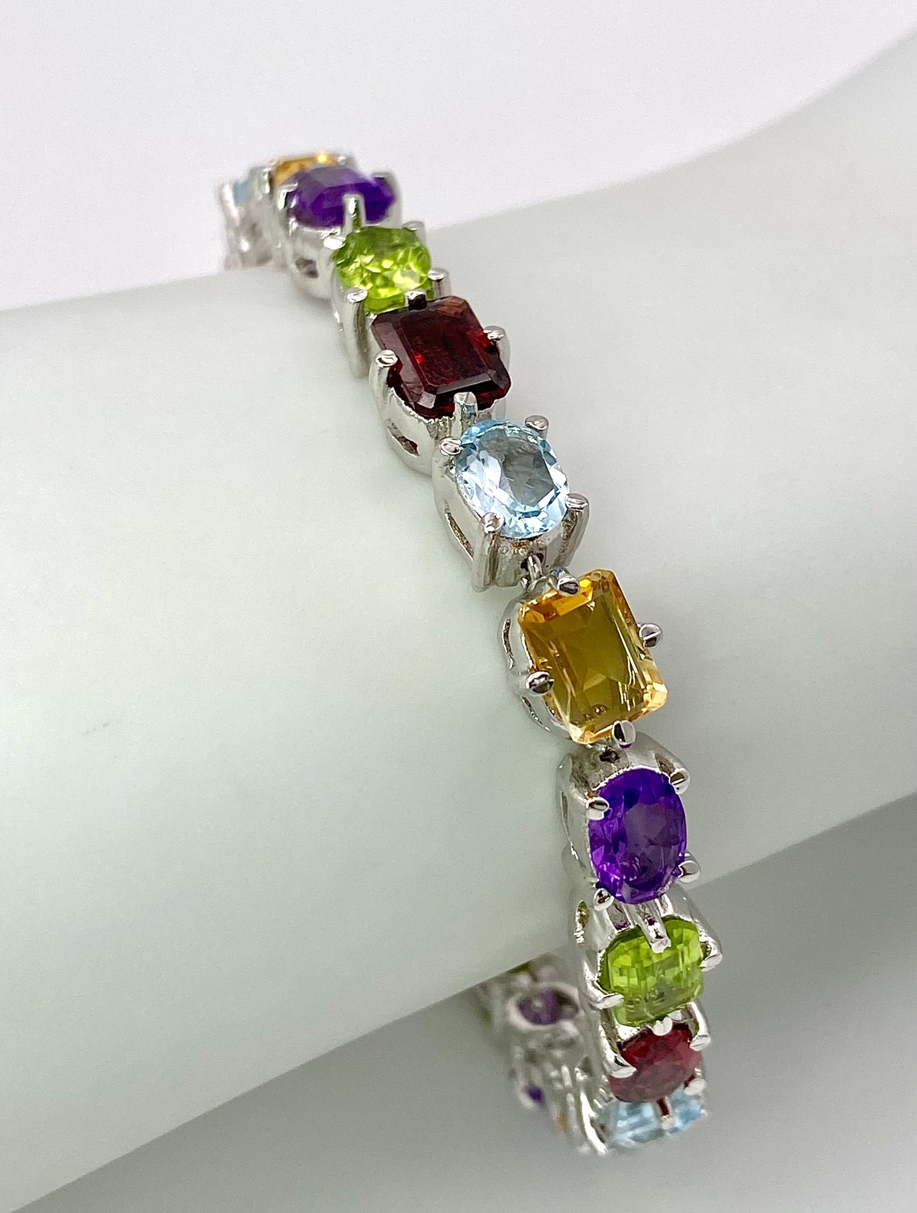 A Multi-Gemstone Bracelet consisting of: Peridots, Amethysts, Blue topaz, Garnet Citrine & Rubies. - Image 3 of 4