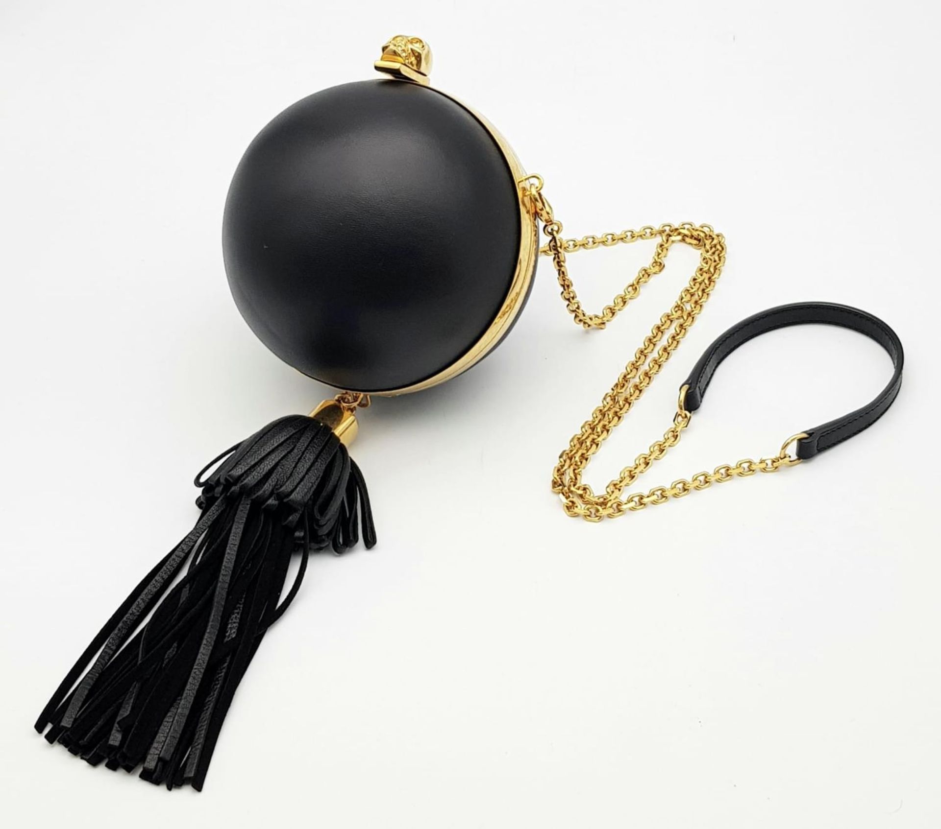 An Alexander Mcqueen Skull Ball Clutch Bag. Black leather exterior with gold tone hardware.