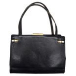 A Gucci Black Hand Bag. Leather exterior with gold-toned hardware, two thin straps, and clasp