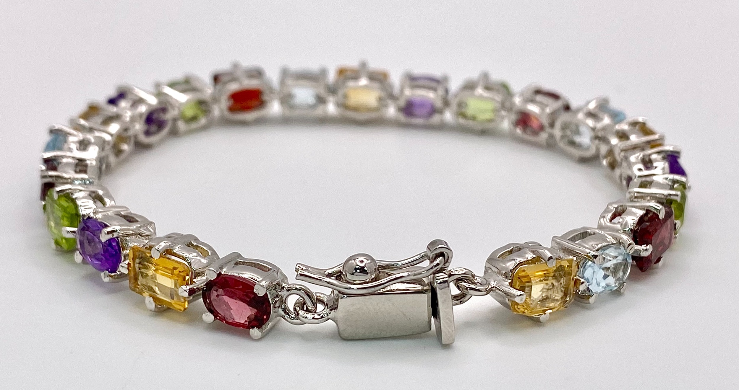 A Multi-Gemstone Bracelet consisting of: Peridots, Amethysts, Blue topaz, Garnet Citrine & Rubies. - Image 2 of 4