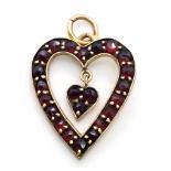 A 9 K yellow gold , heart shaped pendant loaded with garnets, height (with bail): 29 mm, weight: 2.5