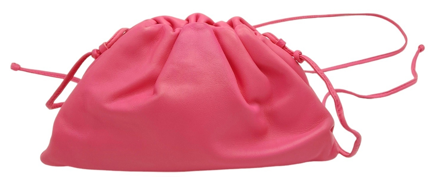 A Bottega Veneta Pink Mini Pouch Bag. Leather exterior with thin strap and magnetic closure. Pink
