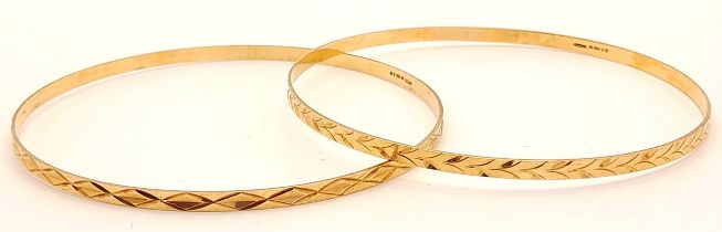 A pair of 9 K yellow gold bangles, each with a different design but perfectly complementing each