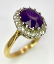 An 18K Yellow Gold Amethyst and Diamond Ring. Central amethyst with a diamond halo. Size M. 4.4g