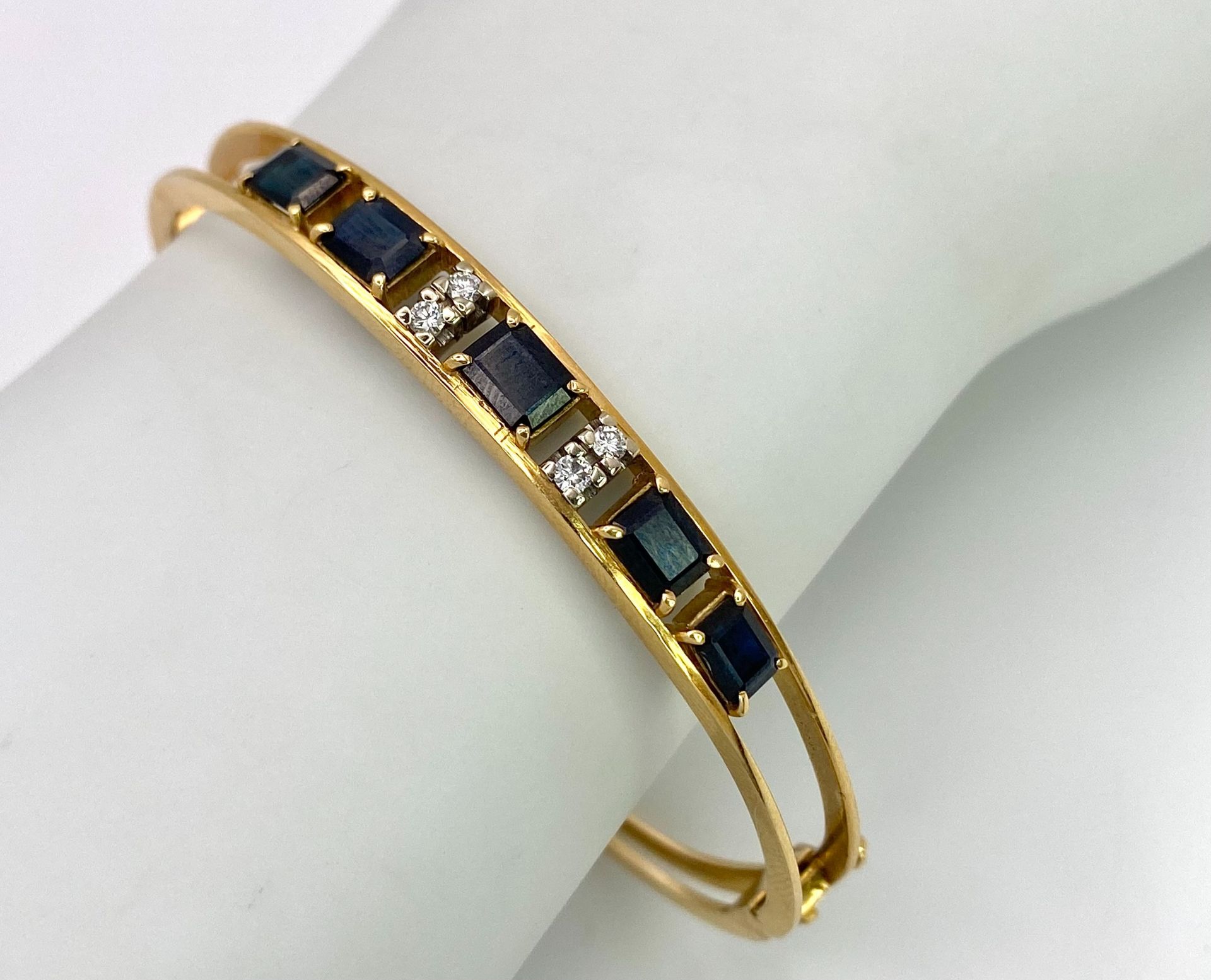 A 14K (TESTED AS) YELLOW GOLD BANGLE SET WITH 5 SAPPHIRES AND 4 DIAMONDS, 6CM DIAMETER, 15.9G (DIA: - Image 2 of 6