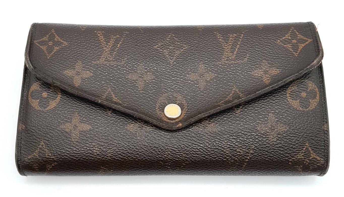 A Louis Vuitton Monogram Wallet. Leather exterior with an open compartment on back and press stud
