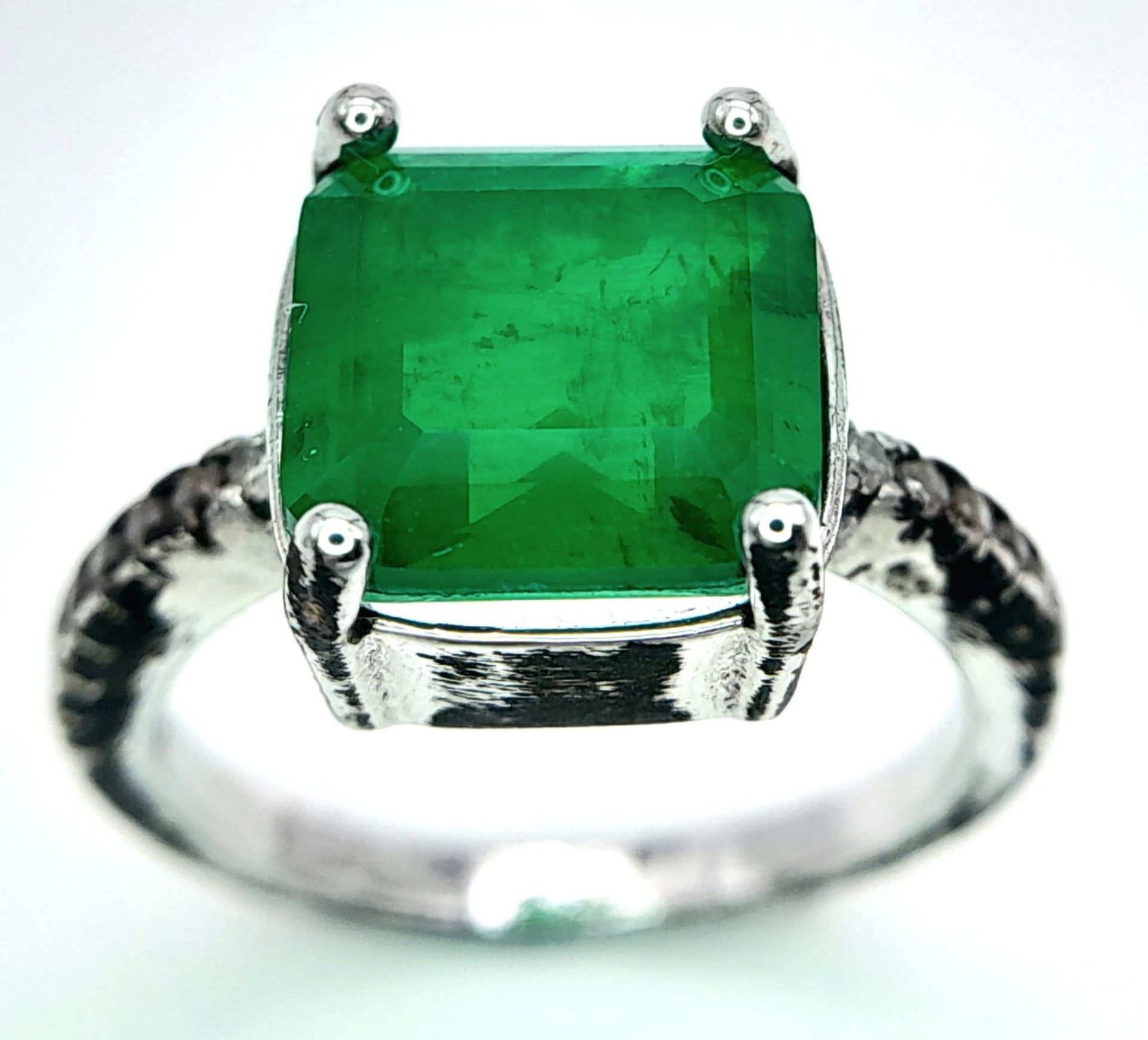 A sterling silver ring with an emerald cut green stone and cubic zirconia on the shoulders. Size: N,