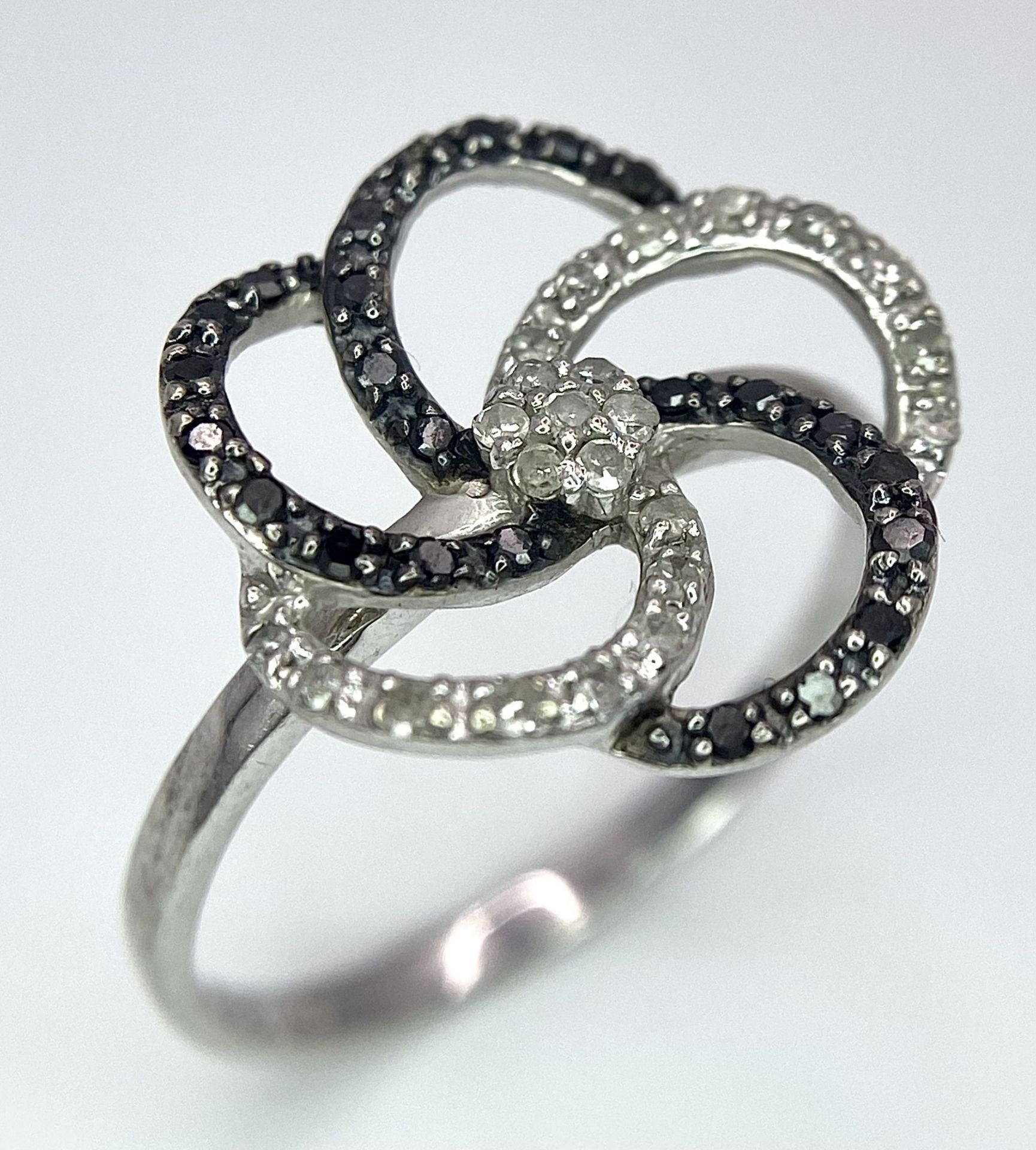 A 9K White Gold Black ad White Diamond Decorative Floral Ring. Size N. 2g total weight.