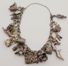 A SILVER CHARM BRACELET WITH OVER 25 INTERESTING CHARMS . 70.9gms