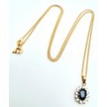 A 9 K yellow gold chain necklace carrying a pendant with an oval cut dark blue sapphire surrounded