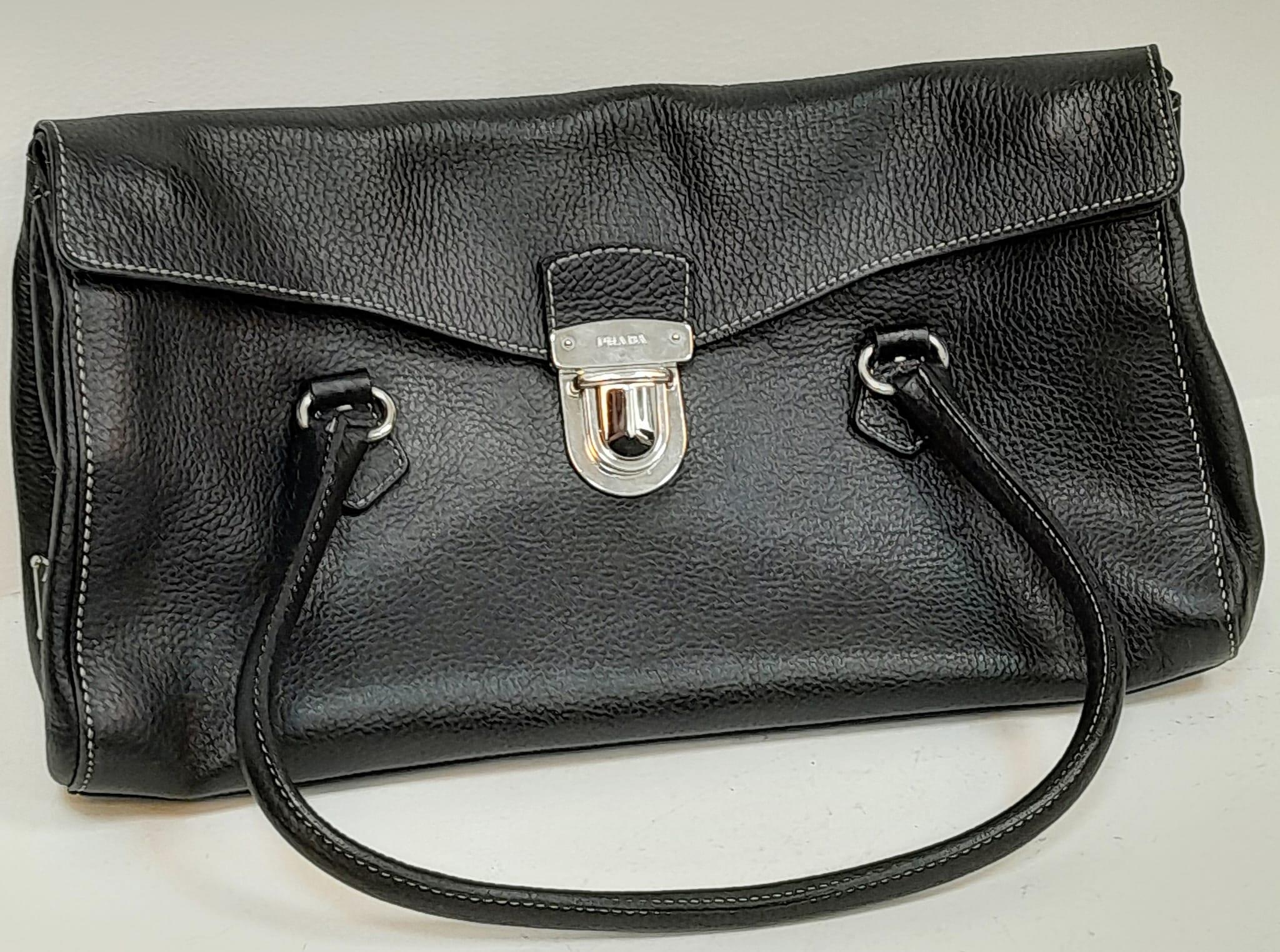 A Prada Black Shoulder Bag. Leather exterior with silver-toned hardware, two rolled leather