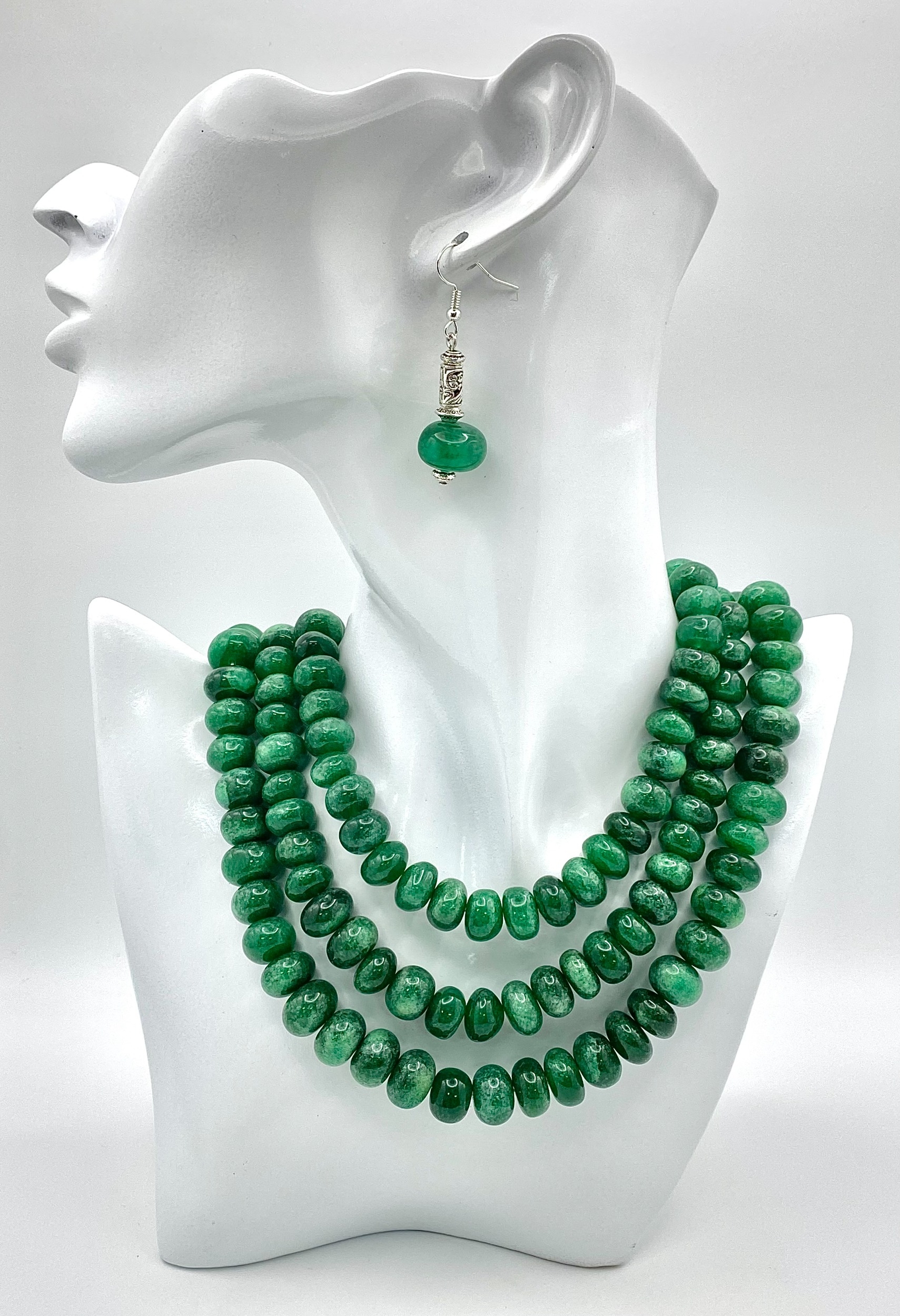 A Tibetan silver necklace with three rows of substantial round emerald cabochons accompanied by a