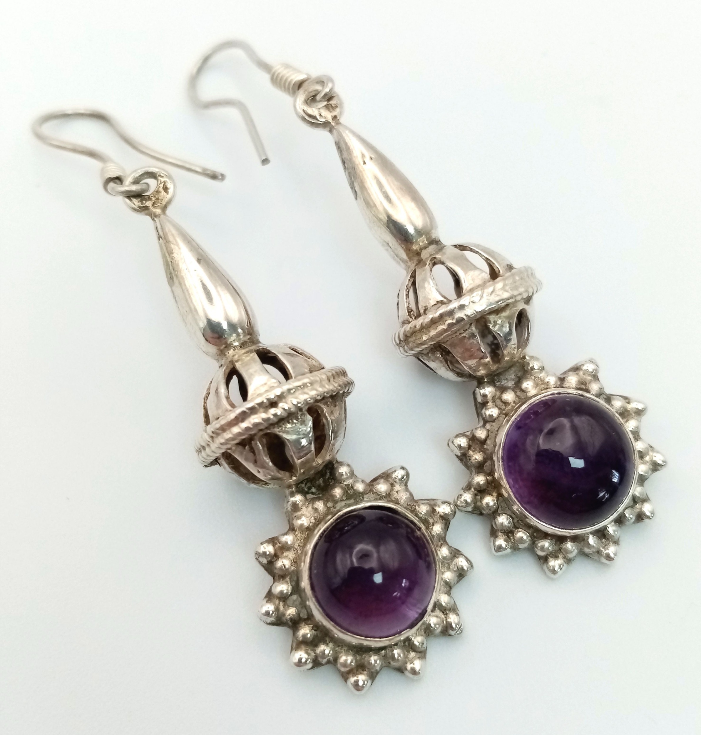 A Pair of Sterling Silver and Amethyst Drop Earrings. Decorative 4cm drops with amethyst cabochons.