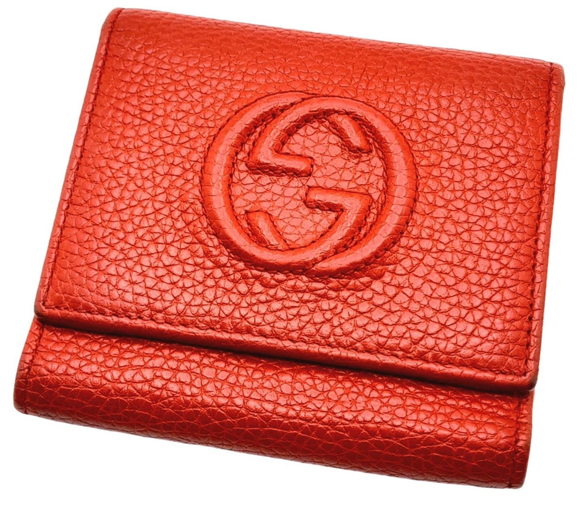 A Gucci Red Trifold Wallet. Leather exterior with the GG logo and press stud closure. Red leather