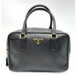 A Prada Black Bauletto Handbag. Saffiano leather exterior with gold-toned hardware, padlock, 2