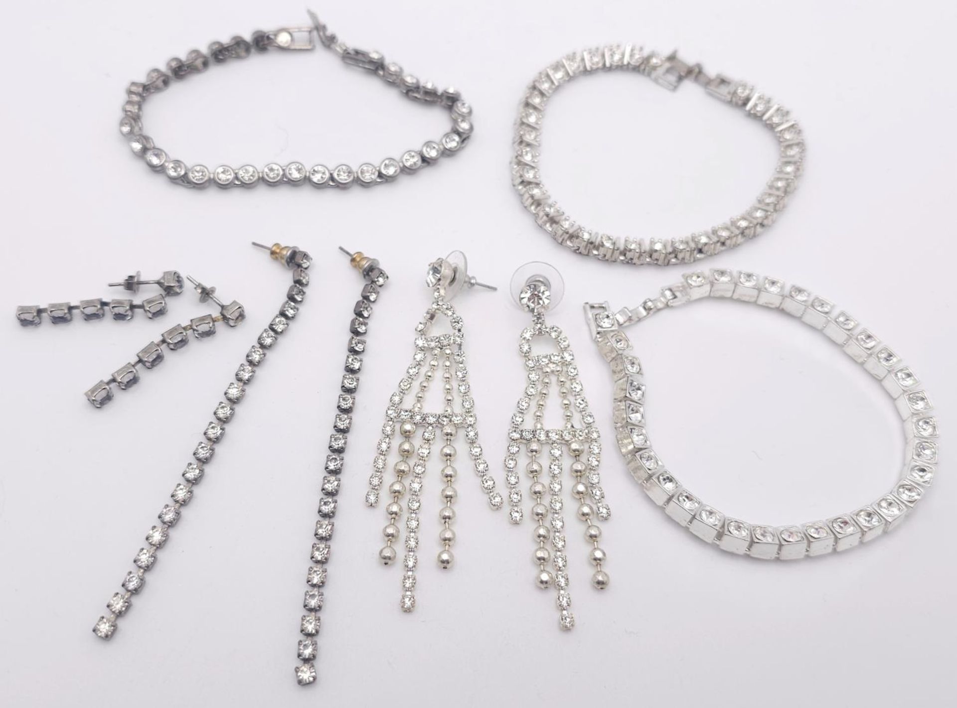 A White metal rhinestone costume bundle including 3x bracelets (all 19cm) and 3 pairs of earrings.