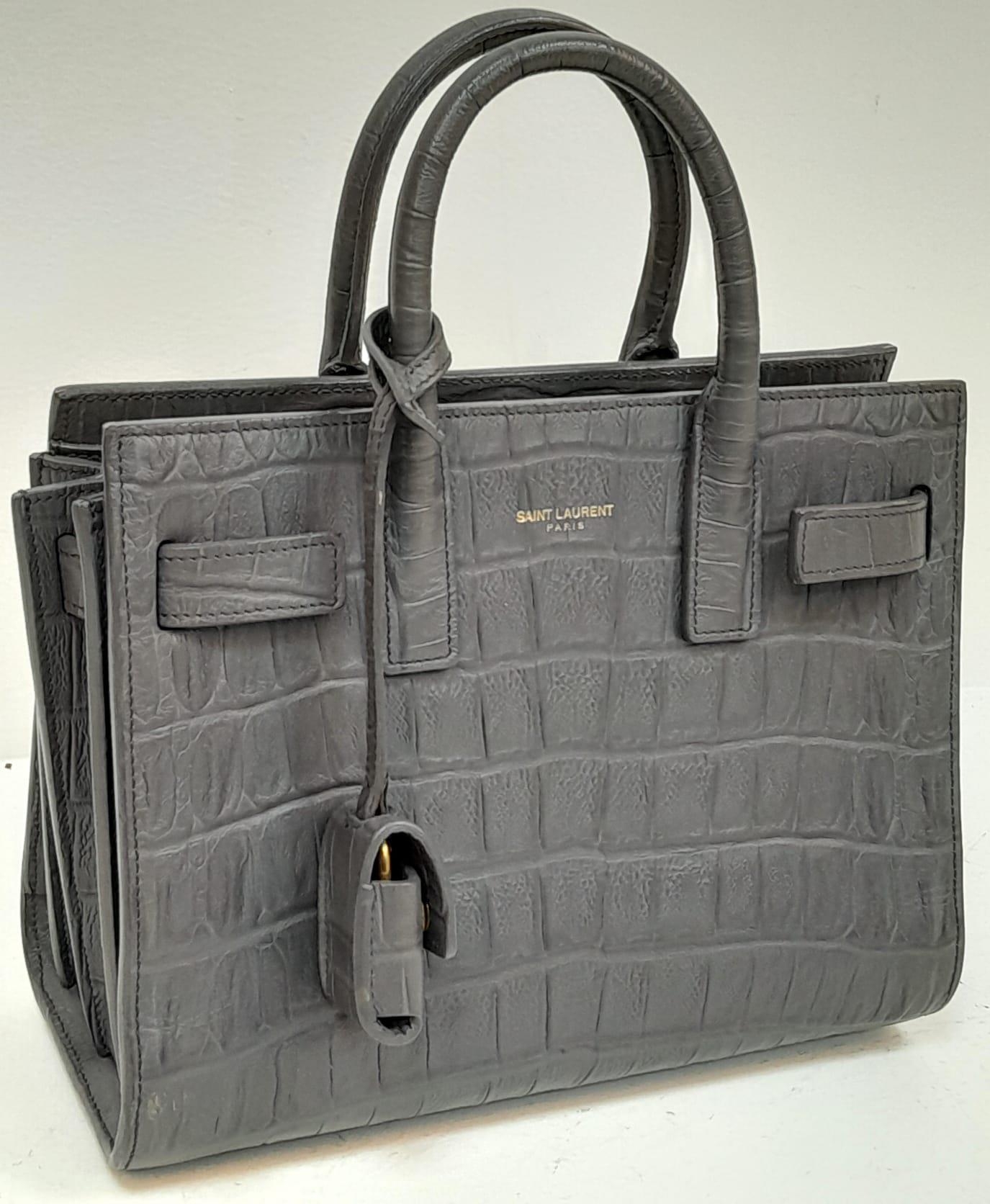 A Saint Laurent Grey Crocodile Embossed Small Sac De Jour Bag. Gold tone padlock (no key). Soft