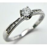 AN 18K WHITE GOLD DIAMOND SOLITAIRE RING - WITH DIAMOND SHOULDERS. 0.25CT. 1.9G. SIZE L