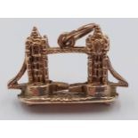 A 9K YELLOW GOLD LONDON TOWER BRIDGE CHARM, WITH MOVING PARTS WHERE THE BRIDGE LIFTS. 2cm x 1.5cm.