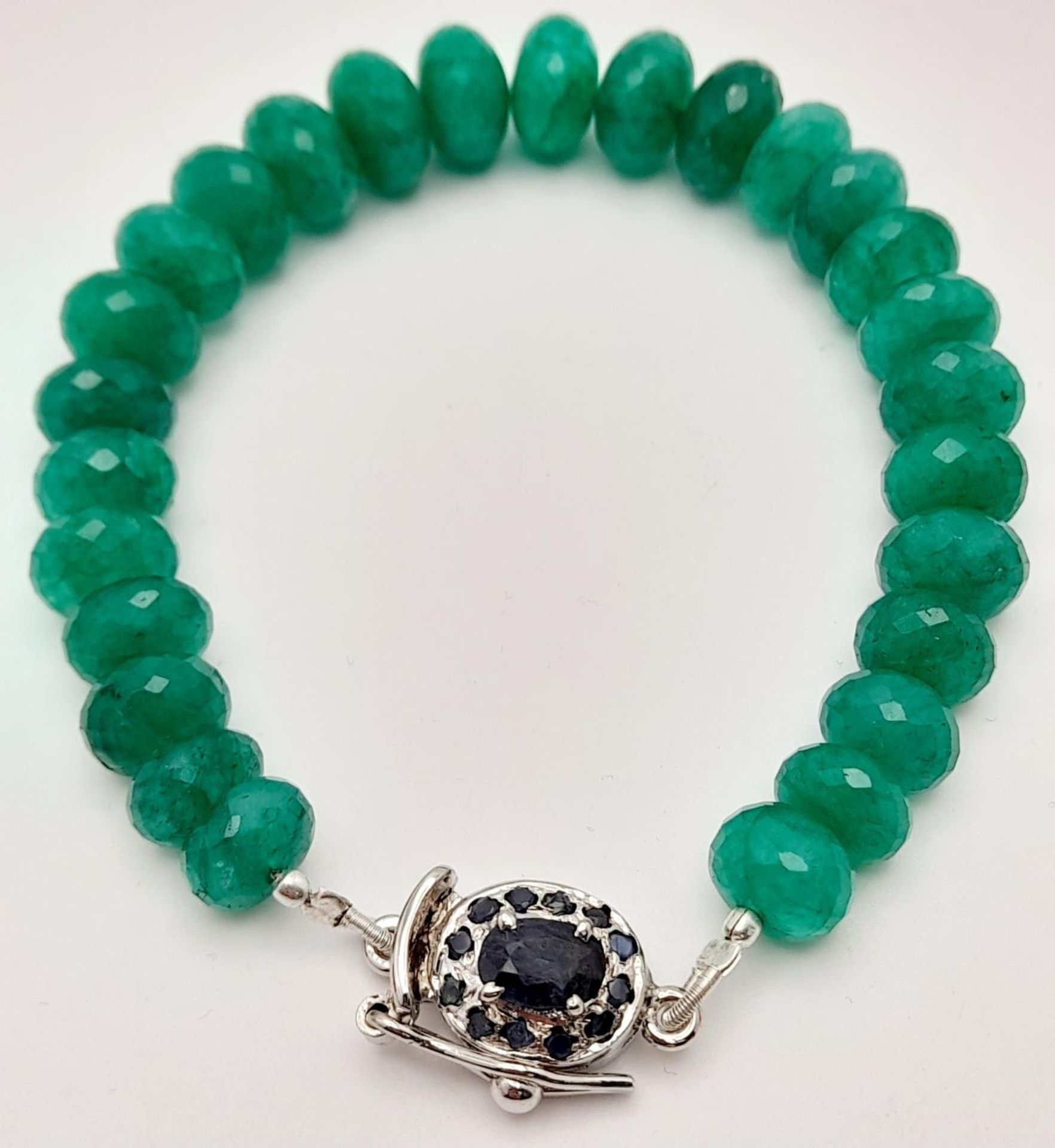 A 130ctw Faceted Rondelle Emerald Bracelet with a sapphire and 925 Silver clasp. 16cm. Ref: CD-1298