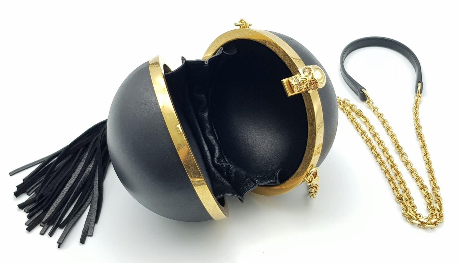 An Alexander Mcqueen Skull Ball Clutch Bag. Black leather exterior with gold tone hardware.