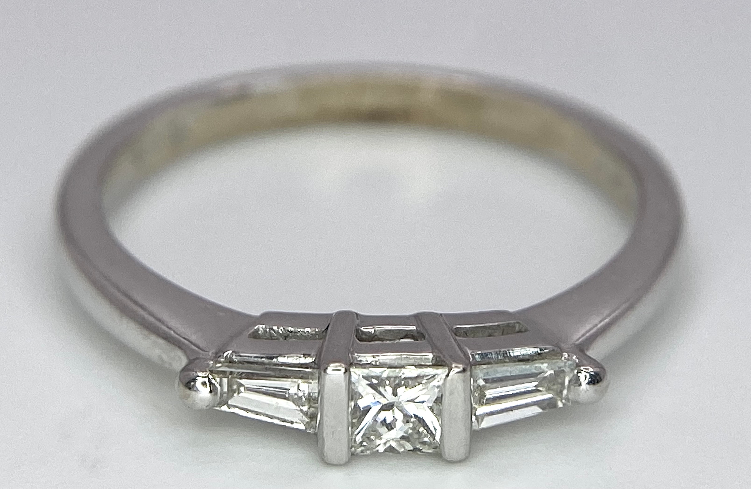 AN 18K WHITE GOLD, DIAMOND 3 STONE RING - PRINCESS CUT CENTRE WITH A TAPPERED BAGUETTE DIAMOND - Image 3 of 7
