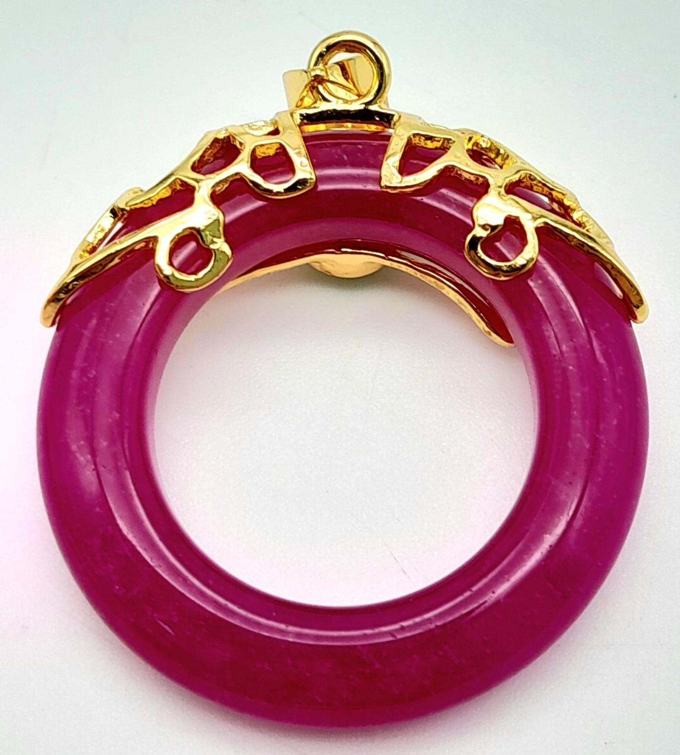 A Magenta Jade Pendant on Gilded Backing. 4cm length, 3cm diameter, 6.79g total weight. - Image 2 of 4