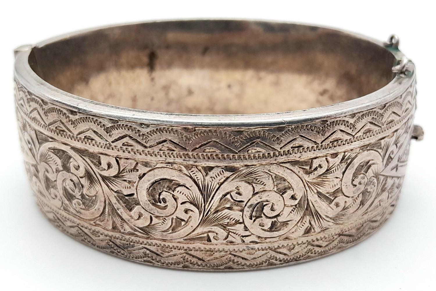 A Silver Victorian Engraved Bangle. 6.3cm diameter, 3cm band width, 43.69g weight.