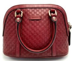 A Gucci Red Guccissima Dome Bag. Monogramed leather exterior with gold-toned hardware, two rolled