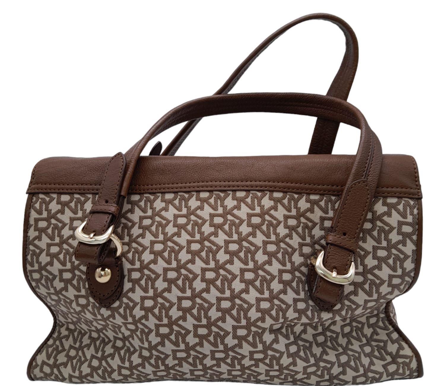A DKNY Brown Satchel Bag. Canvas and leather exterior with gold-toned hardware, four protective base