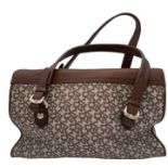 A DKNY Brown Satchel Bag. Canvas and leather exterior with gold-toned hardware, four protective base