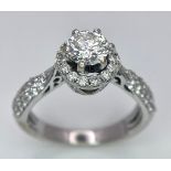 An 18K White Gold Diamond Ring. Central 0.75ct brilliant round cut diamond with a diamond halo and